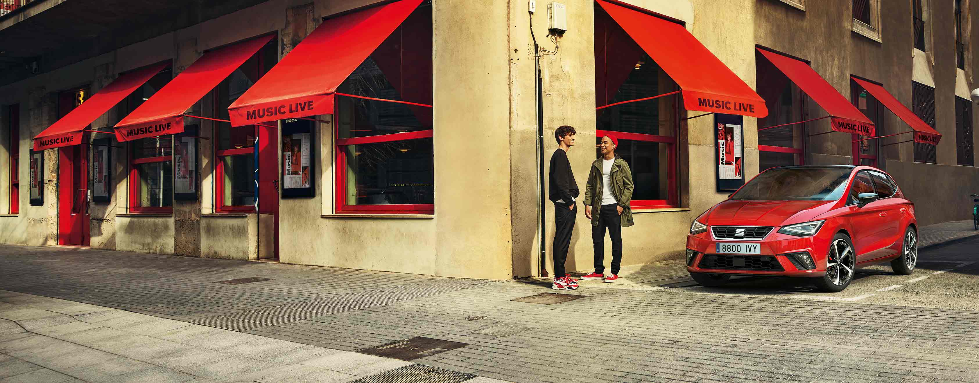 two friends in front side view of the red SEAT Ibiza